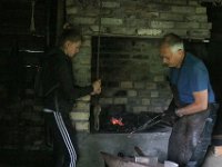 For å få full varme i essa, så må man dra i belgsnora, for å blåse luft på kullene. Smed-drengen henger i snora.